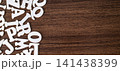 Few scattered white wooden letter tiles on empty dark brown wooden background, minimalist typography concept 141438399