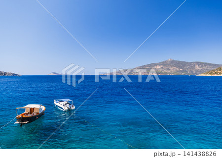 Two small boats tethered on a vibrant blue sea with clear skies Two small boats tethered on a vibrant blue sea with clear skies 141438826