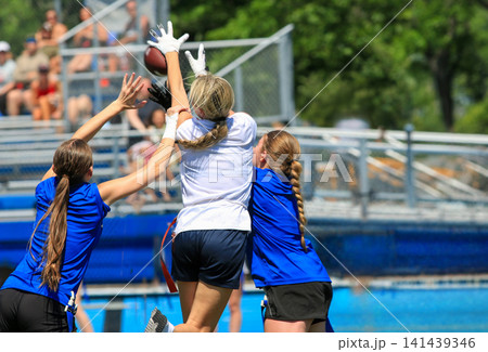 Three Girls Jumpi8ng to Catch a Football in the End Zone During a Flag Football Game Three Girls Jumpi8ng to Catch a Football in the End Zone During a Flag Football Game 141439346