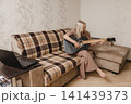 Mature woman playing guitar beside a laptop at home 141439373