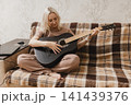Mature woman practicing acoustic guitar at home 141439376