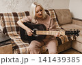 Happy mature woman playing acoustic guitar at home 141439385