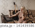 Mature woman talking on a smartphone while using a laptop 141439386