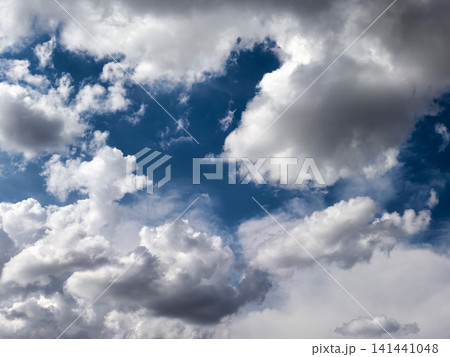 Dramatic White and Gray Cumulus Clouds in Blue Sky 141441048