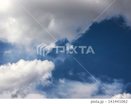 Dramatic White and Gray Clouds Against Deep Blue Sky 141441062