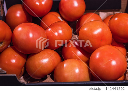 Closeup of fresh red ripe tomatoes displayed in a black crate at a grocery store store. Closeup of fresh red ripe tomatoes displayed in a black crate at a grocery store store. 141441292