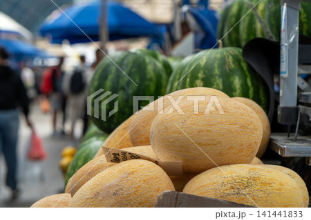 Ripe and juicy melons lie on the counter in the market or bazaar. Sale of ripe and fresh vegetables and fruits at the farmers' market. Close-up. Ripe and juicy melons lie on the counter in the market or bazaar. Sale of ripe and fresh vegetables and fruits at the farmers' market. Close-up. 141441833