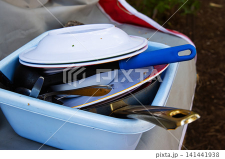 A blue plastic basin full of used dishes, pans, and utensils after a meal at a forest campsite in Finland. 141441938