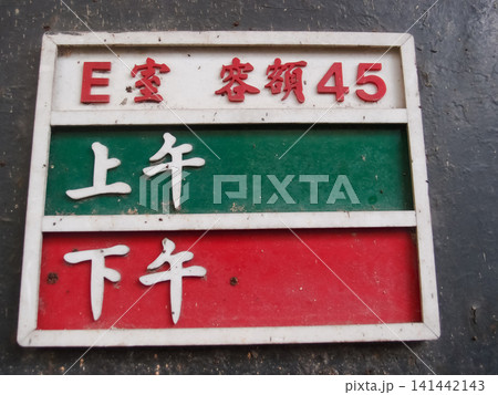 Close-up of the information sign in abandoned primary school. Translation: Room E, Capacity 45 people and Morning and Afternoon. Close-up of the information sign in abandoned primary school. Translation: Room E, Capacity 45 people and Morning and Afternoon. 141442143
