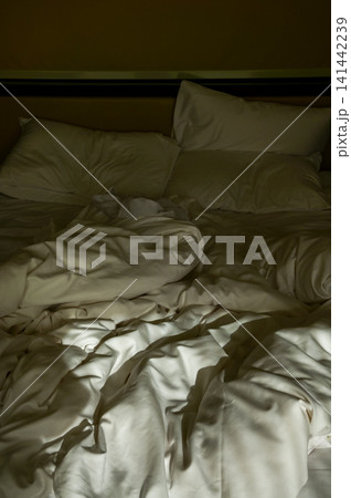Close-up of the bed with white sheet in the room. Hotel or apartment scene. Close-up of the bed with white sheet in the room. Hotel or apartment scene. 141442239