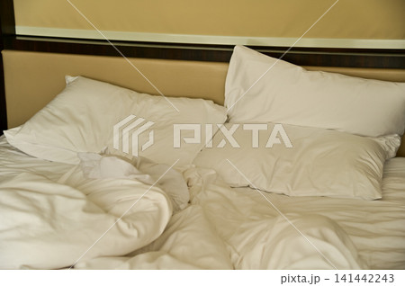 Close-up of the bed with white sheet in the room. Hotel or apartment scene. Close-up of the bed with white sheet in the room. Hotel or apartment scene. 141442243