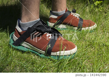 Lawn aerator shoes on grass, illustrating practical garden maintenance for healthy turf and simple manual soil care in home yards. Lawn aerator shoes on grass, illustrating practical garden maintenance for healthy turf and simple manual soil care in home yards. 141442390