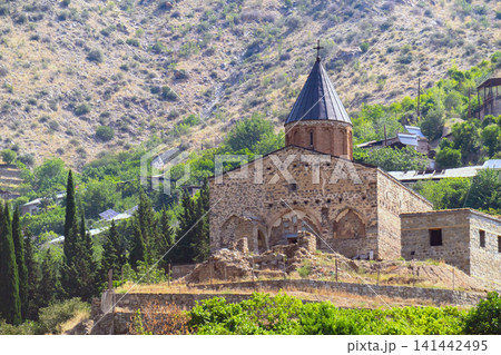 Stone-built church with pointed roof, surrounded by lush greenery Stone-built church with pointed roof, surrounded by lush greenery 141442495