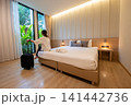 Female tourist sitting on bed in comfortable hotel bedroom. Conceptual shot of a place for someone to stay, live, or work temporary. 141442736