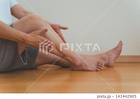 40代男性が床に座ってふくらはぎをセルフマッサージするシーン 40代男性が床に座ってふくらはぎをセルフマッサージするシーン 141442905
