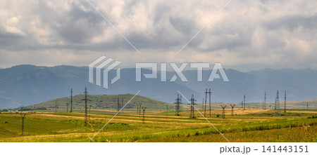 Cloudy sky over rolling hills with power poles across grassy field Cloudy sky over rolling hills with power poles across grassy field 141443151