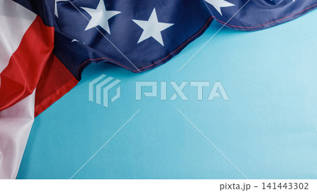 American flag draped over the top frame on a vibrant blue background with copy space for text. High Quality Photo American flag draped over the top frame on a vibrant blue background with copy space for text. High Quality Photo 141443302