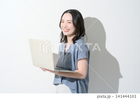 白背景でノートパソコンを持って微笑む日本人女性 白背景でノートパソコンを持って微笑む日本人女性 141444101