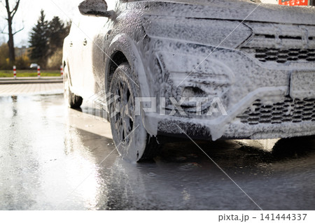 White car completely covered in active snow foam at self-service car wash. White car completely covered in active snow foam at self-service car wash. 141444337