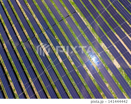 Solar panels on a large field showing rows of solar energy technology under bright sunlight during midday hours 141444442