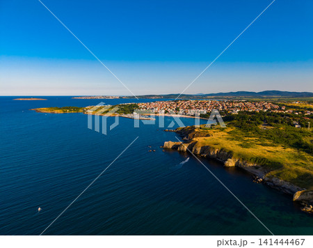 Coastal view of a town by the sea with hills and clear blue skies during daylight 141444467