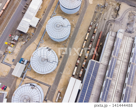 Birds eye view of storage tanks and trains in an industrial area with solar panels during daytime 141444488