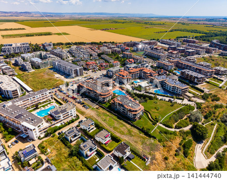 Aerial view of a residential area with houses, pools, and green fields in the background during daytime Aerial view of a residential area with houses, pools, and green fields in the background during daytime 141444740