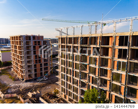 Building construction site with cranes and new structures in progress during daylight 141444769