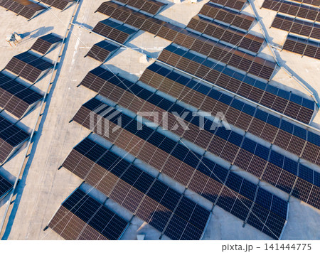 Solar panels installed on a large rooftop in a sunny location during daylight hours 141444775