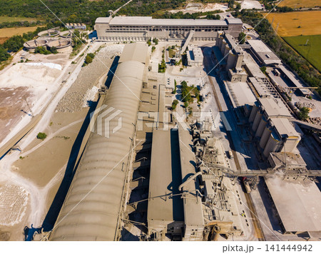 Industrial facility located in a rural area surrounded by fields and trees showing large structures and machinery Industrial facility located in a rural area surrounded by fields and trees showing large structures and machinery 141444942