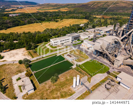 View of industrial area with buildings and green spaces near a factory in a sunny location during the day 141444971
