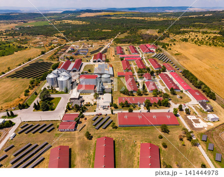 Farm located in a rural area with storage units and agricultural fields in the background under a clear sky 141444978