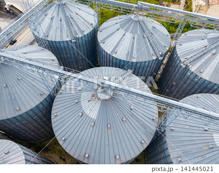 Rows of large metal silos used for grain storage in an agricultural area during daylight Rows of large metal silos used for grain storage in an agricultural area during daylight 141445021