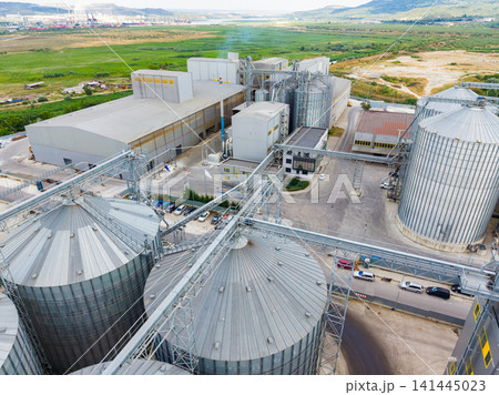 View of a grain storage facility and processing plant in a rural area with silos and large buildings during daytime 141445023