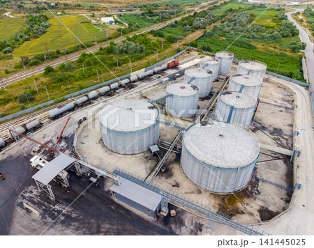 Storage tanks and railway cars at an industrial facility in a rural area during daytime Storage tanks and railway cars at an industrial facility in a rural area during daytime 141445025