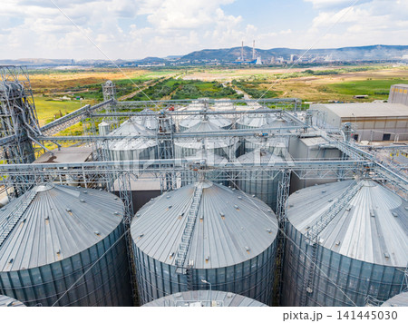 View of large silos in a farming area near a power plant with open fields and distant mountains View of large silos in a farming area near a power plant with open fields and distant mountains 141445030