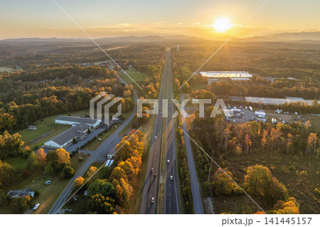Freeway road with fast moving traffic cars and trucks in American rural area in fall season at sunset. Interstate transportation infrastructure in USA Freeway road with fast moving traffic cars and trucks in American rural area in fall season at sunset. Interstate transportation infrastructure in USA 141445157