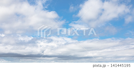 Sky with fluffy white cirrus clouds forming a soft atmospheric pattern. Natural background of blue sky with scattered white clouds and sunlight. Sky with fluffy white cirrus clouds forming a soft atmospheric pattern. Natural background of blue sky with scattered white clouds and sunlight. 141445195