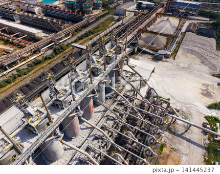 Industrial site with multiple processing units and conveyor systems in operation during daytime hours Industrial site with multiple processing units and conveyor systems in operation during daytime hours 141445237