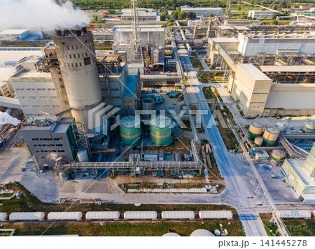 Industrial site with large structures, pipes, tanks, and steam in a manufacturing area during daytime Industrial site with large structures, pipes, tanks, and steam in a manufacturing area during daytime 141445278