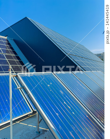 Solar panels installed on a building roof under clear blue sky during daytime while generating renewable energy and supporting eco-friendly practices 141445419