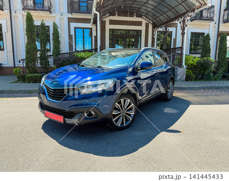 Modern car parked in front of a building with greenery on a sunny day in an urban area Modern car parked in front of a building with greenery on a sunny day in an urban area 141445433