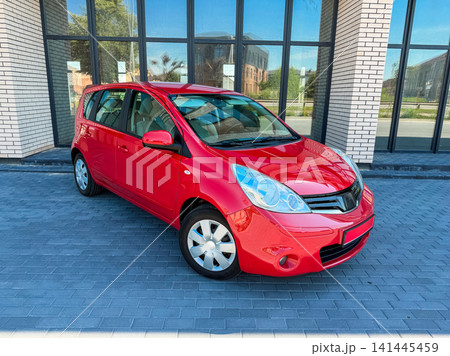 Car parked in front of a modern building on a sunny day with clear skies, showcasing vibrant colors and a sleek design while highlighting the surrounding architecture Car parked in front of a modern building on a sunny day with clear skies, showcasing vibrant colors and a sleek design while highlighting the surrounding architecture 141445459