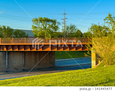 Bridge over a road with grass and trees nearby during the late afternoon in a suburban area Bridge over a road with grass and trees nearby during the late afternoon in a suburban area 141445477