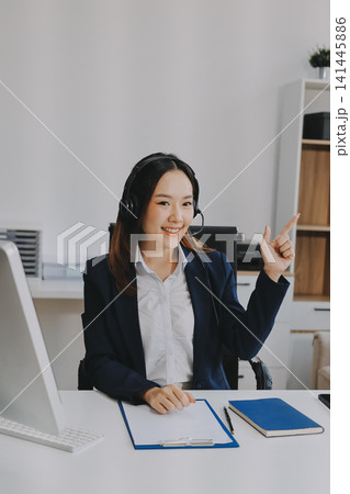 Smiling Asian Woman Telemarketing Agent with Headset Working at Smiling Asian Woman Telemarketing Agent with Headset Working at 141445886