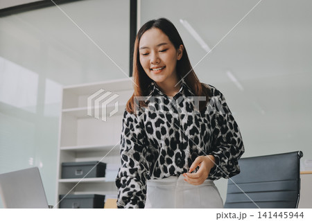 Confident asian business woman standing in modern office Confident asian business woman standing in modern office 141445944