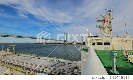 High angle view from oil tanker vessel deck moving in bay toward Verrazzano Narrows Bridge with city skyline background in New York for maritime shipping industry High angle view from oil tanker vessel deck moving in bay toward Verrazzano Narrows Bridge with city skyline background in New York for maritime shipping industry 141446113