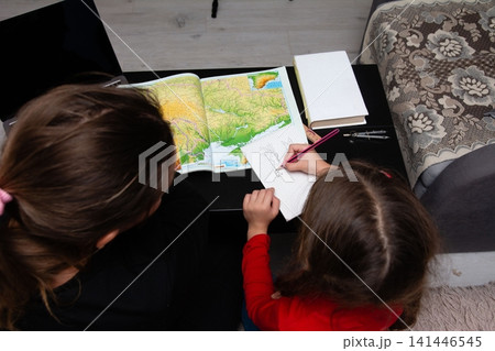 Young girl drawing and learning about geography with her mother at home, family time, education, creativity and bonding. 141446545