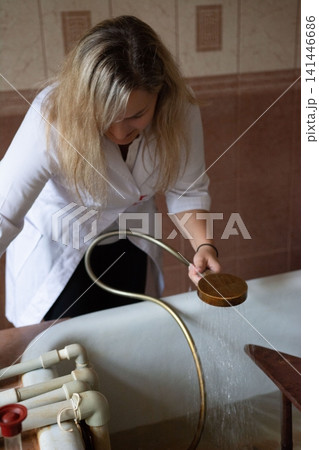 Woman operating hydrotherapy equipment, showcasing specialized bathing treatment with running water for health and wellness in a clinic. Woman operating hydrotherapy equipment, showcasing specialized bathing treatment with running water for health and wellness in a clinic. 141446686