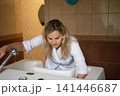 A professional fills a bathtub with water. She is wearing a white shirt and is working in a bathroom that is clean. 141446687